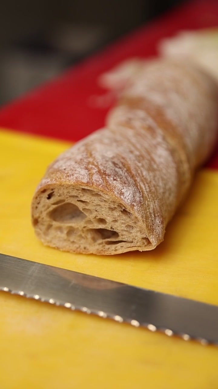 Primo piano di una baguette affettata su un tagliere giallo