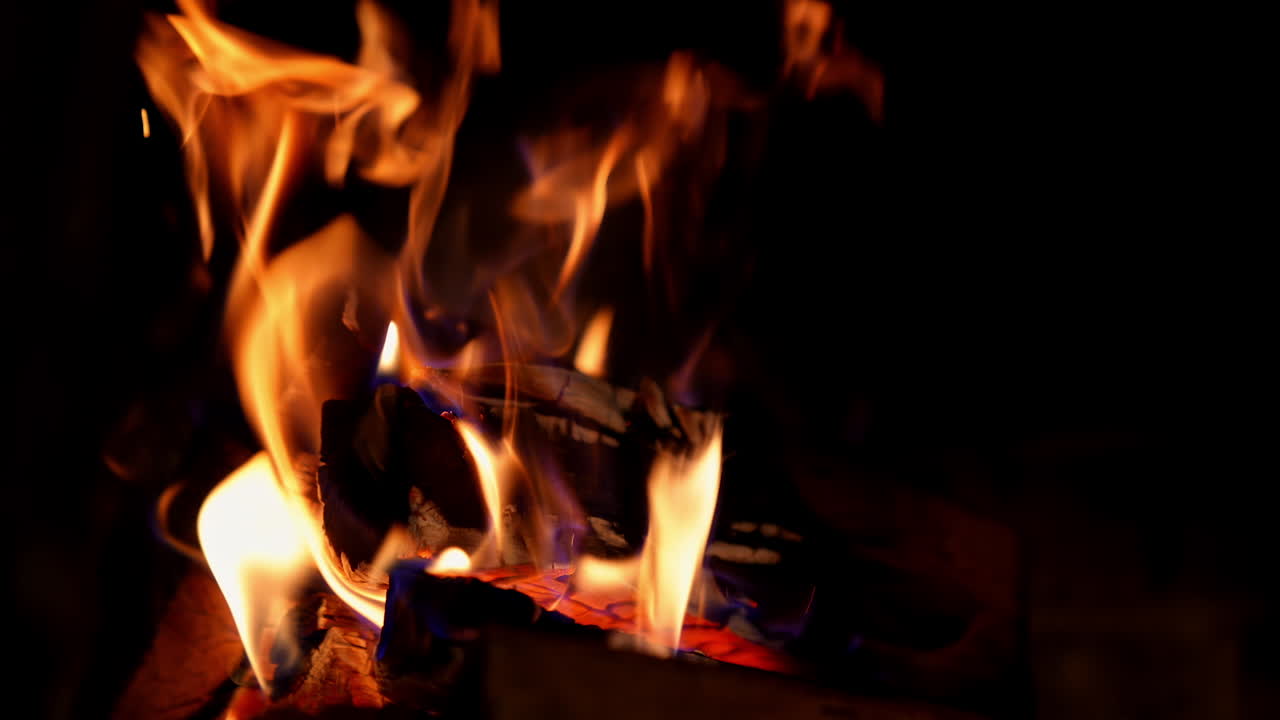 Red and orange tongues of fire on black background. Wood burning in vivid flame in the fireplace. Glowing fire at night. Close-up.