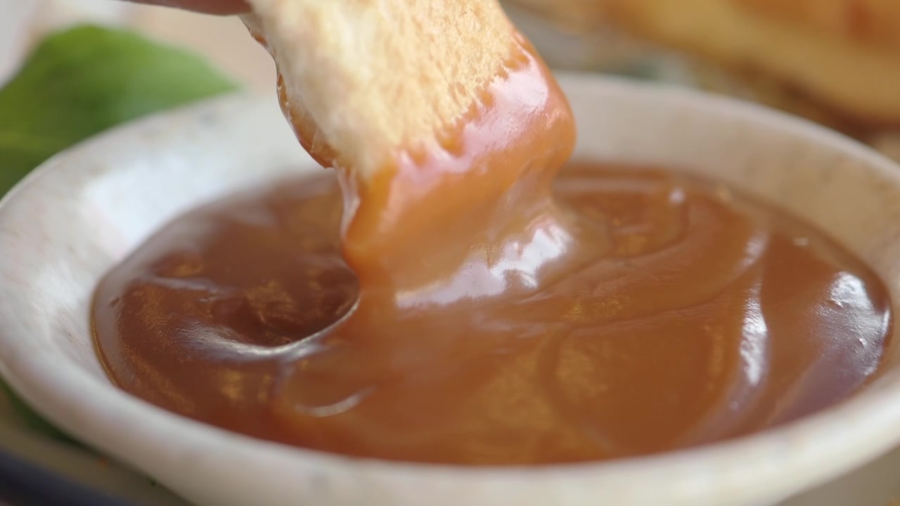 Stykke brød dyppet i tyk karamelsauce