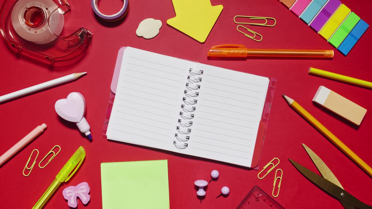 Stationery cycles around a spiral notebook with copy space on red background, loopable stop motion animation