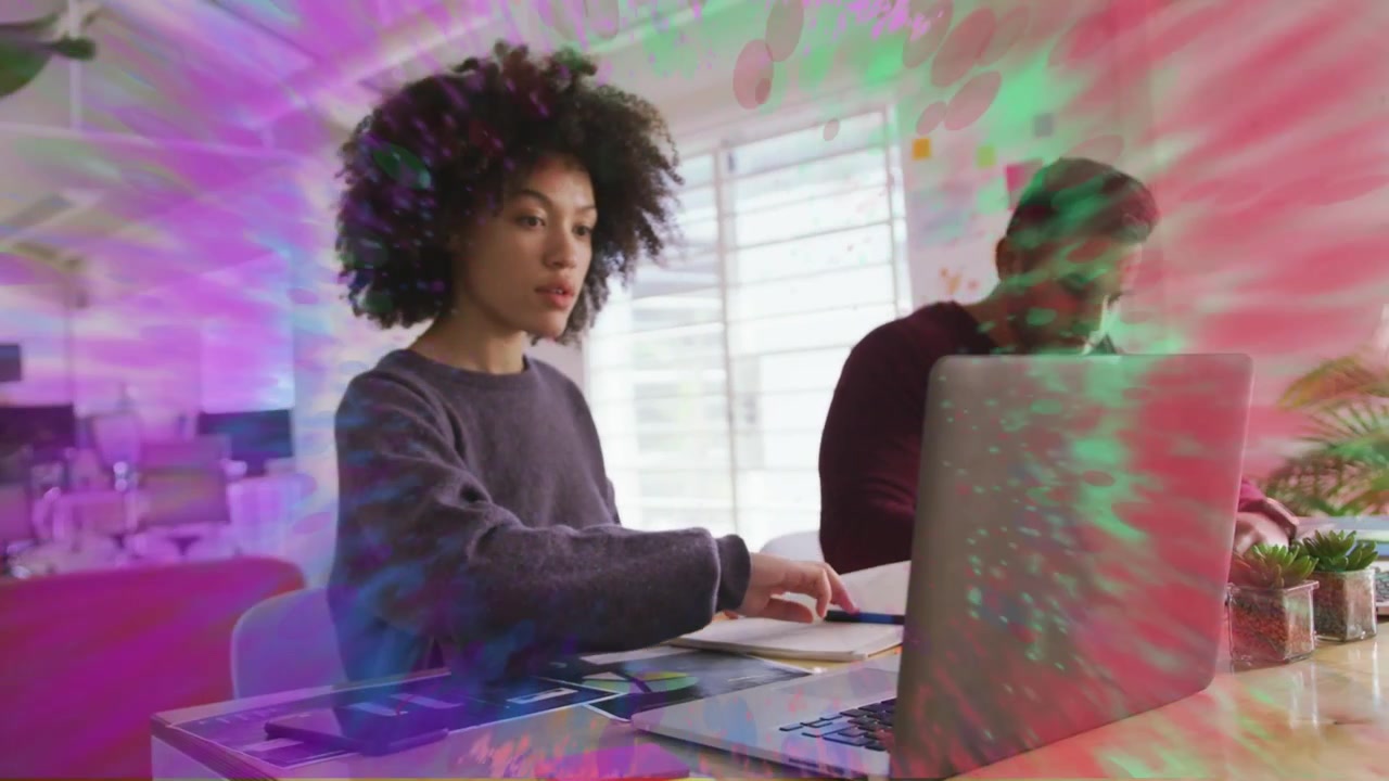 Woman typing PC in office initiating pulsing overlay, glancing watch, writing notes for project