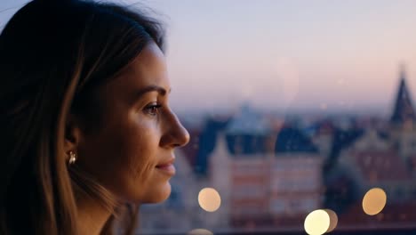 woman looking out window at cityscape at night