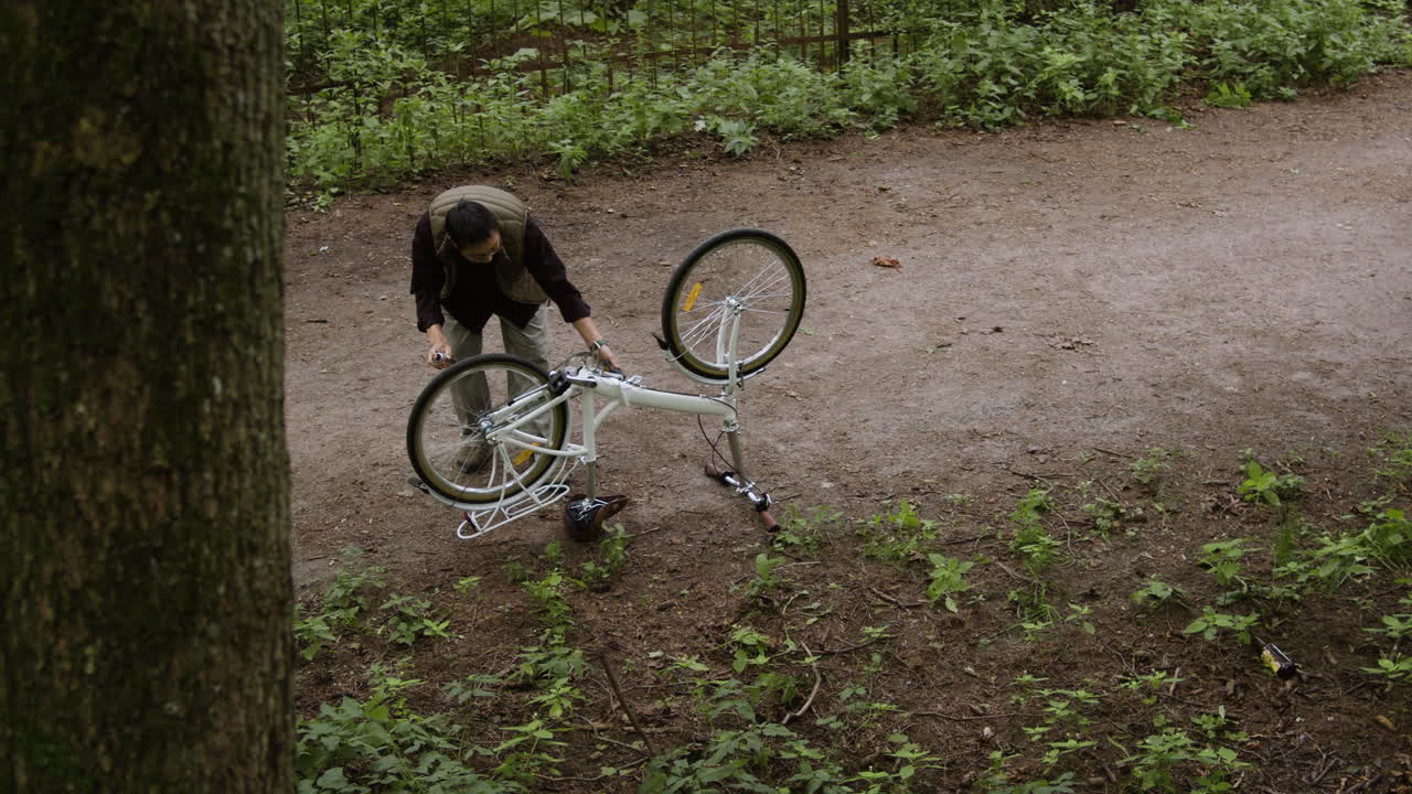 Man Repairing Bicycle in Forest