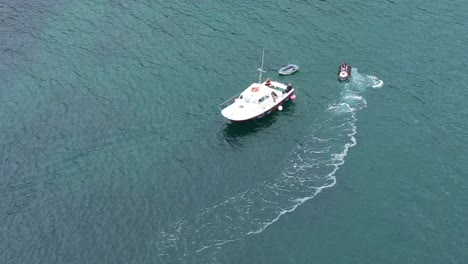 Toma-De-órbita-Aérea-De-Una-Moto-De-Agua-Y-Un-Bote-Pequeño-En-La-Costa-De-Cornualles,-Reino-Unido