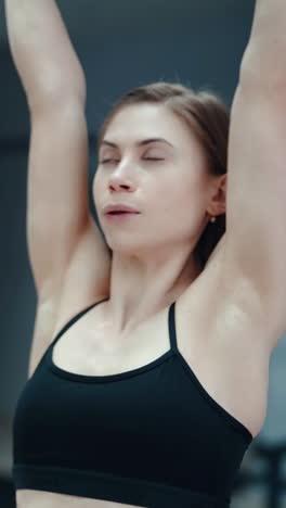 slim woman in a black top and leggings performs an exercise with her hands with dumbbells in the gym. sport equipment. blurred background vertical video