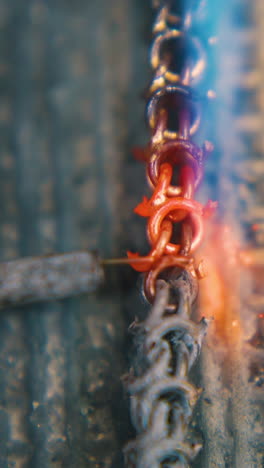 cu shot: welding of gold metal chain links with jeweler needle and gas burner on fireproof asbestos sheet closeup