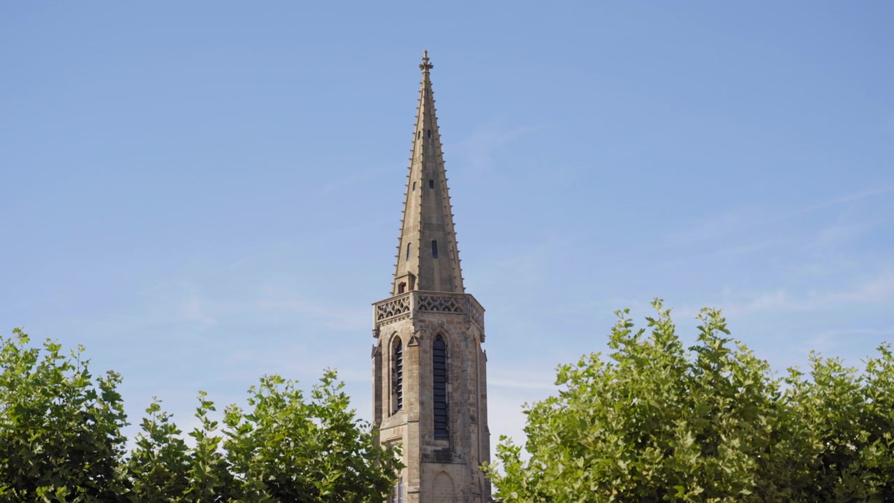 Torre histórica da Igreja de São Luís erguendo-se acima de árvores verdes contra um céu azul claro em Saarlouis, Alemanha