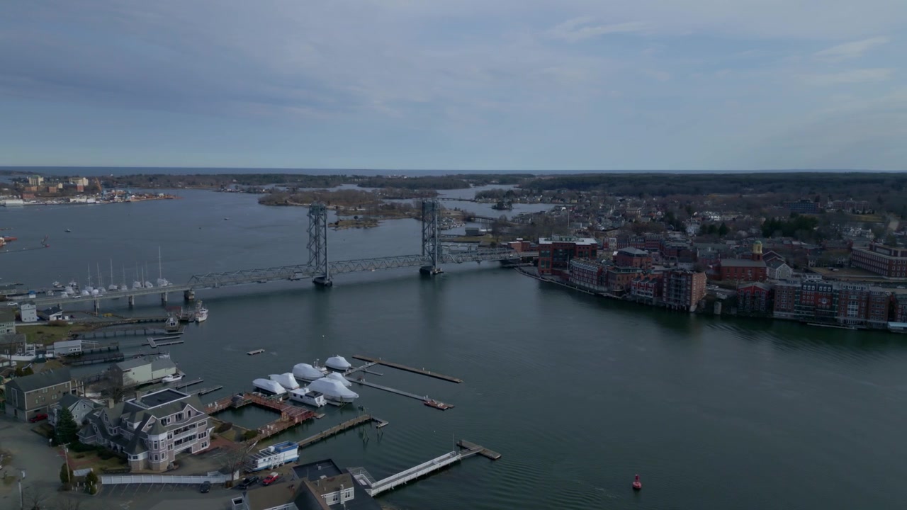 Panoramica aerea introduttiva del porto di Portsmouth e del ponte commemorativo, con moli, barche ancorate e acque calme