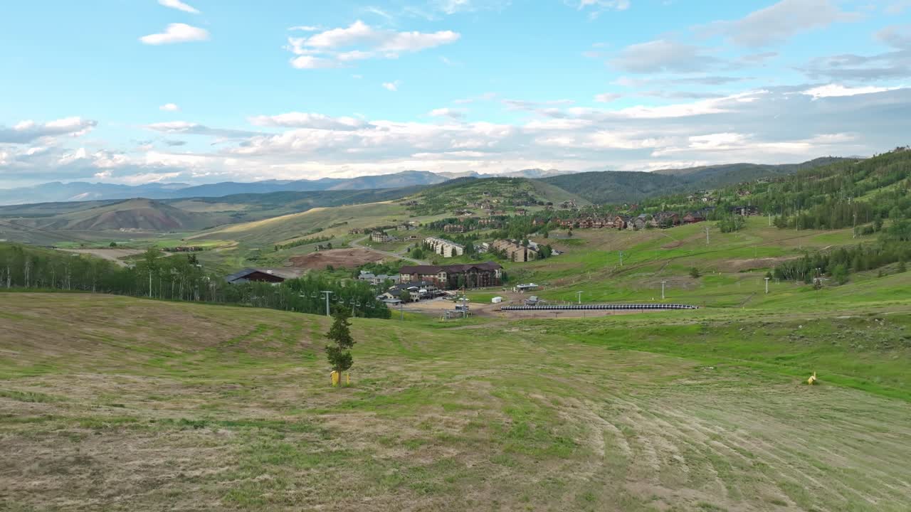 retiro aéreo por encima de la ladera verde inclinada de la estación de esquí en verano con las épicas montañas de colorado