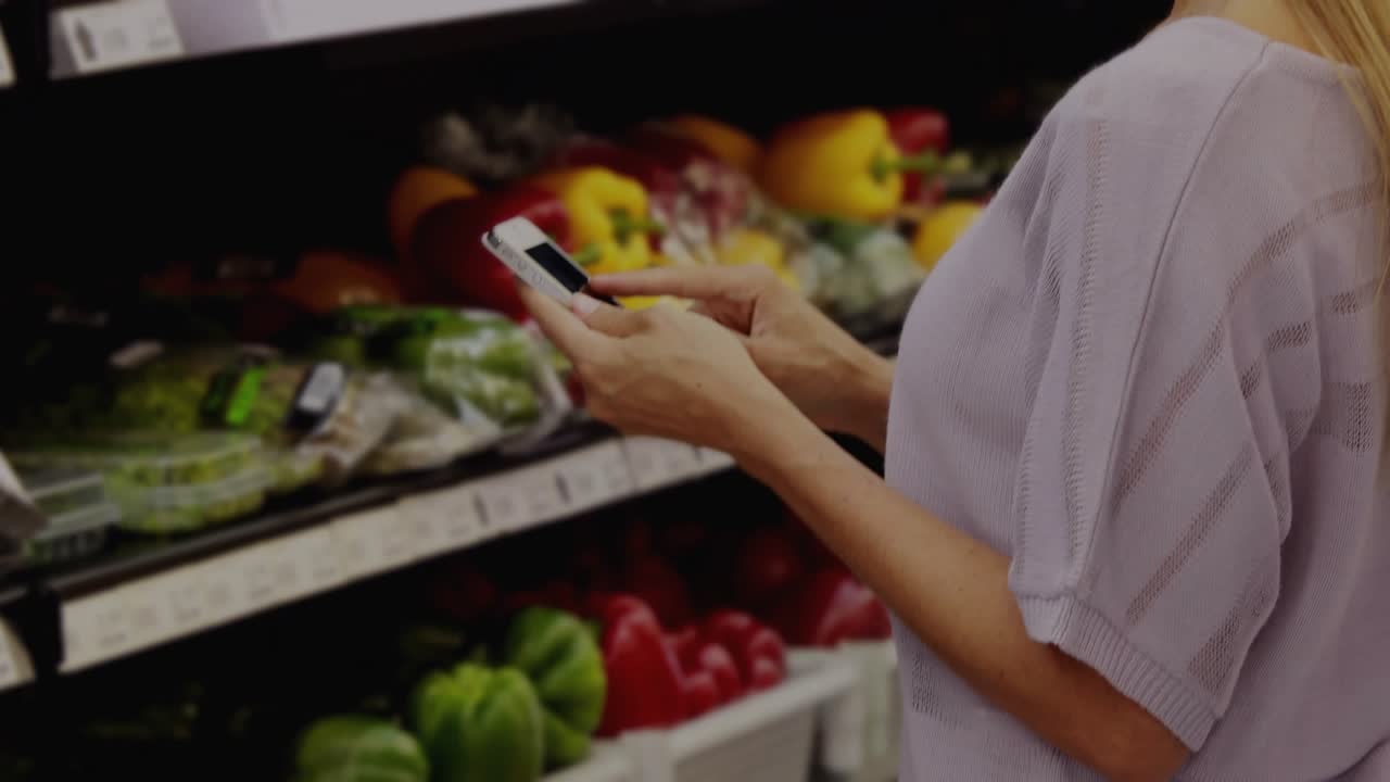 Woman shopping tapping phone, pointing at produce in grocery aisle, light streaks guiding choice