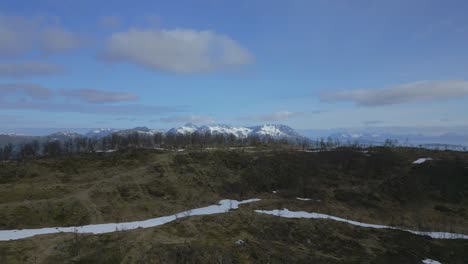 farmland nestled in rolling hills with snow-capped mountains and clear skies in the background