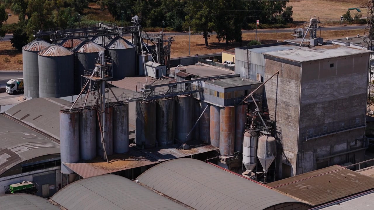 Vista aérea de um grande complexo industrial com silos de grãos, tanques de armazenamento e instalações de processamento para produtos agrícolas