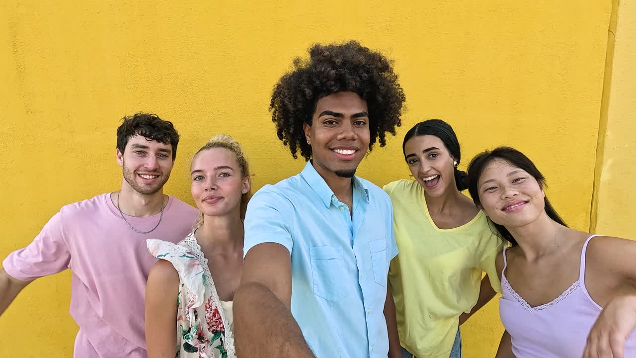 Group of friends taking a selfie against a yellow wall