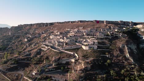 Avión-Teledirigido-En-Movimiento-Hacia-Adelante-Sobre-Casas-Adosadas-De-Urgup-A-Lo-Largo-De-La-Colina-Temenni-En-La-Región-De-Capadocia-De-Turquía-Durante-El-Día