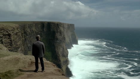 a person standing on a cliff overlooking a stormy ocean