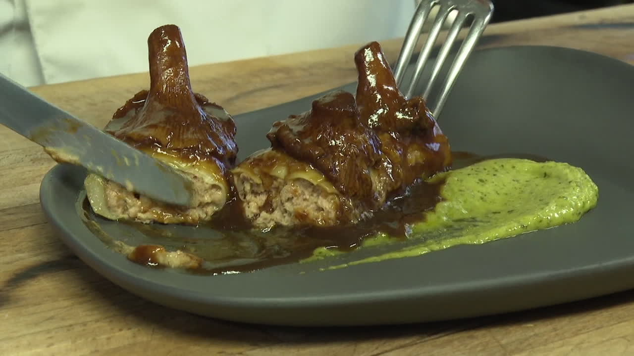 Chef preparing and plating a gourmet dish with mushrooms and meat rolls