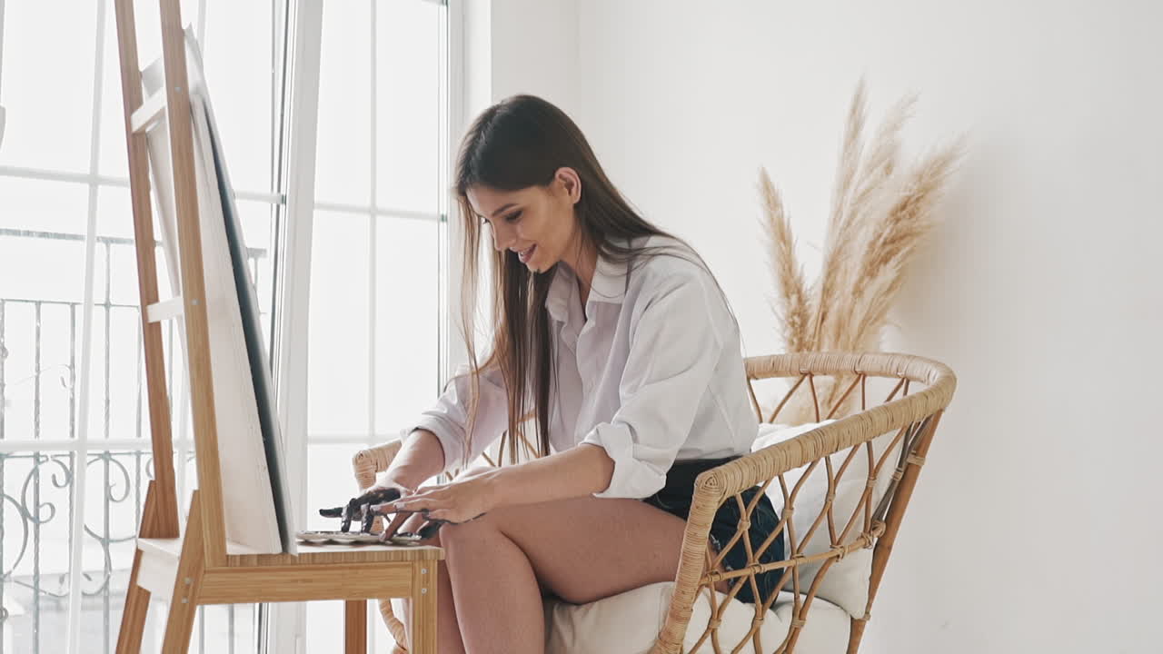 la dama emocional toma pinturas con los dedos dibuja un cuadro en el caballete