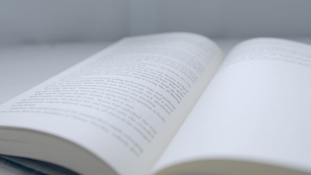 close up shot of finger flip a page of the book from left to right side on desk near window at home