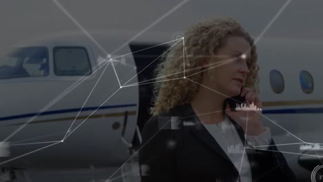 Animation-of-networks-of-connections-over-caucasian-businesswoman-talking-on-smartphone-at-airport