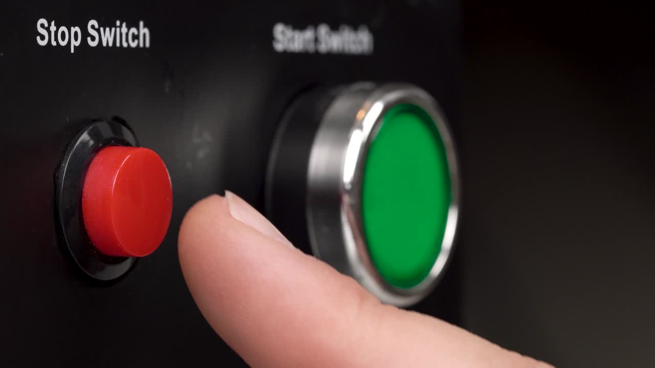 프레임에 있는 두 개의 버튼의 클로즈업. 녹색 시작 스위치와 빨간색 정지 스위치 버튼. 손가락으로 빨간 정지 스위치를 누르십시오.
