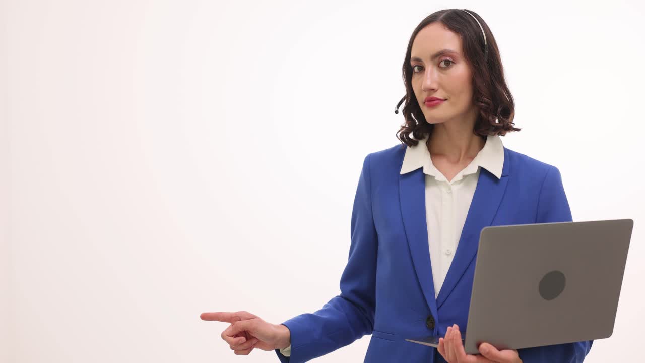 Woman in Blue Suit with Headset and Laptop Pointing to Empty Space