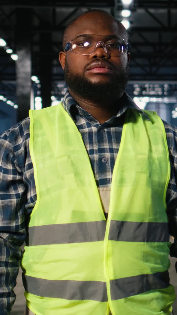 Vertical Video Industrial worker stands near steel machinery during construction tasks