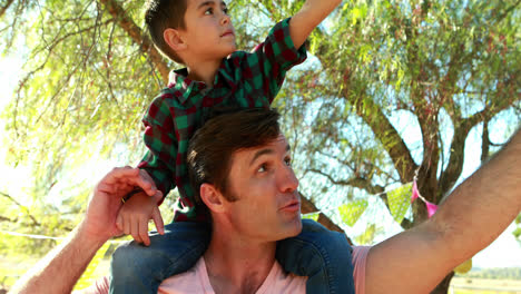 padre feliz cargando a su hijo en el hombro en el parque 4k