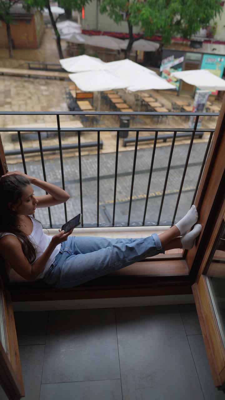 mujer en un balcón en una ciudad lluviosa