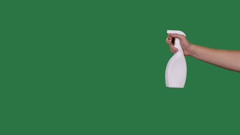 male hand holds a spray bottle and sprays a disinfectant alcohol agent to disinfect the covid 2019 corona virus. green screen, chroma key. slow motion. close up