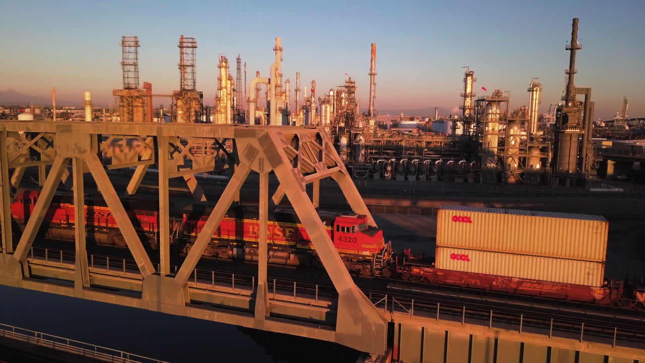 Freight train crossing the railway iron bridge while transporting cargo inland. Aerial parallax view with a flock of the birds entering the frame