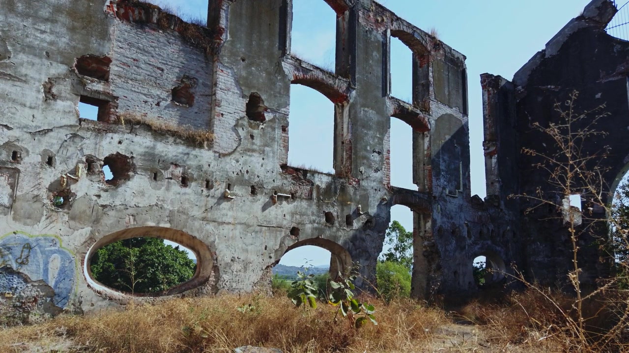 Ruinas de hacienda abandonada con muros de piedra desgastados, ventanas arqueadas y abertura circular en Hacienda Coahuixtla, México.