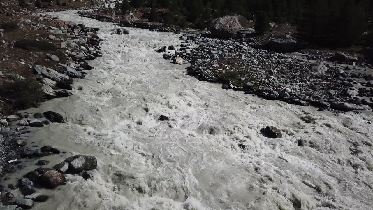 arroyo fangoso en las montañas, fuerte corriente y débito, agua proveniente del glaciar, valle rocoso de los alpes suizos, vista aérea de drones