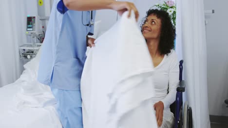 front view of african american female doctor helping disabled female patient in ward at hospital