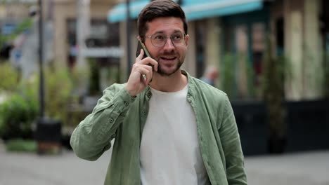 retrato de un hombre guapo con gafas hablando por teléfono en la calle. joven hombre de negocios hablando en teléfono inteligente en la calle, al aire libre, gadget usando concepto.