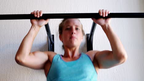 Female-boxer-performing-exercise-on-hanging-bar