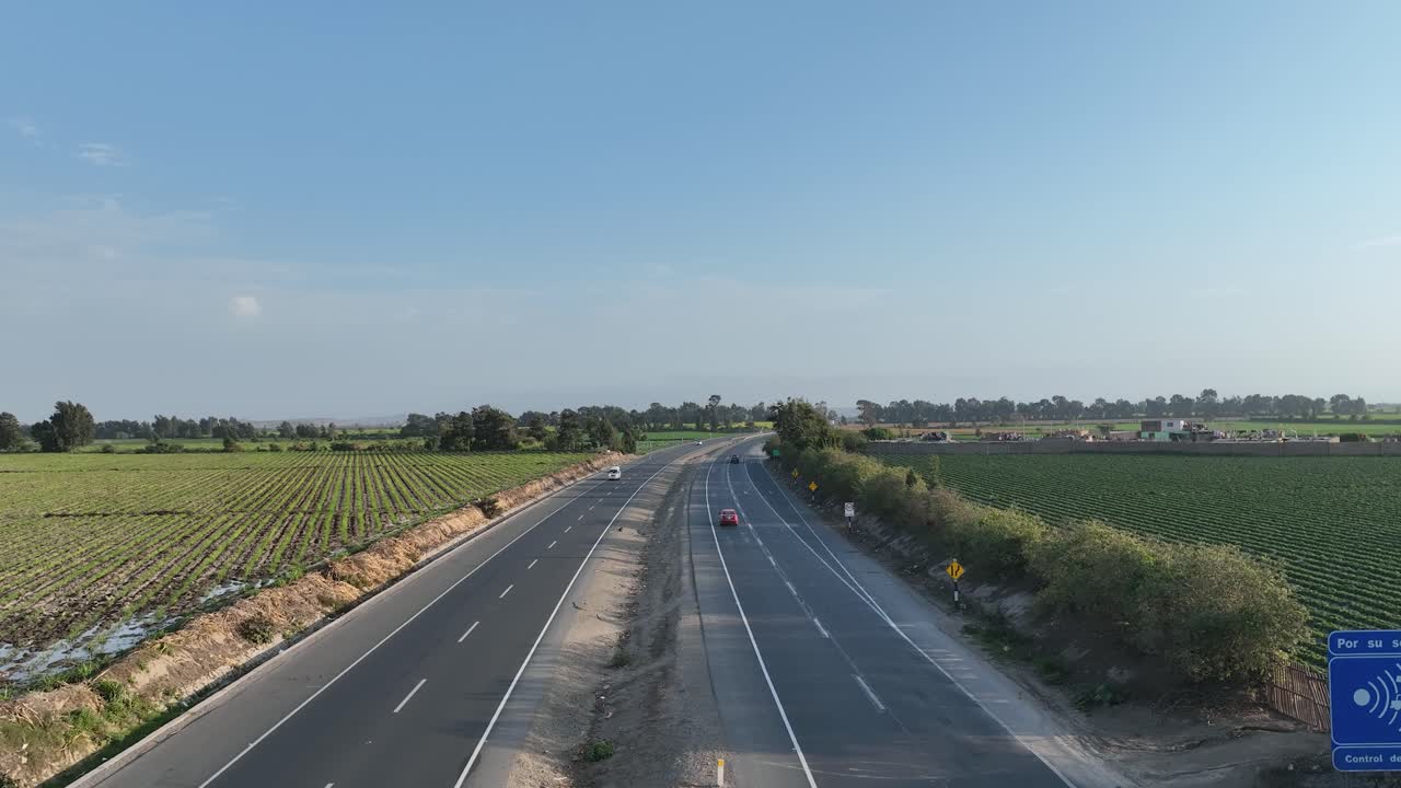 페루의 4차선 파나메리카나 노르테 고속도로를 가로지르는 자동차, 버스 및 운송 차량의 영화 같은 공중 드론 샷은 낮에 양쪽 모퉁이에 있는 비옥한 농지를 통해