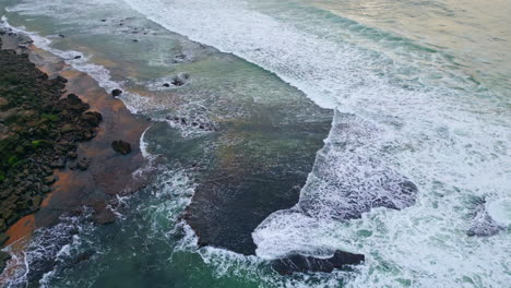 foggy sea covering beach drone view. rippling waves washing volcanic pebbles