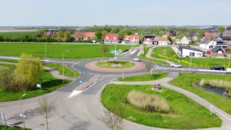 a small roundabout in the netherlands surrounded by green fields and a town in the background