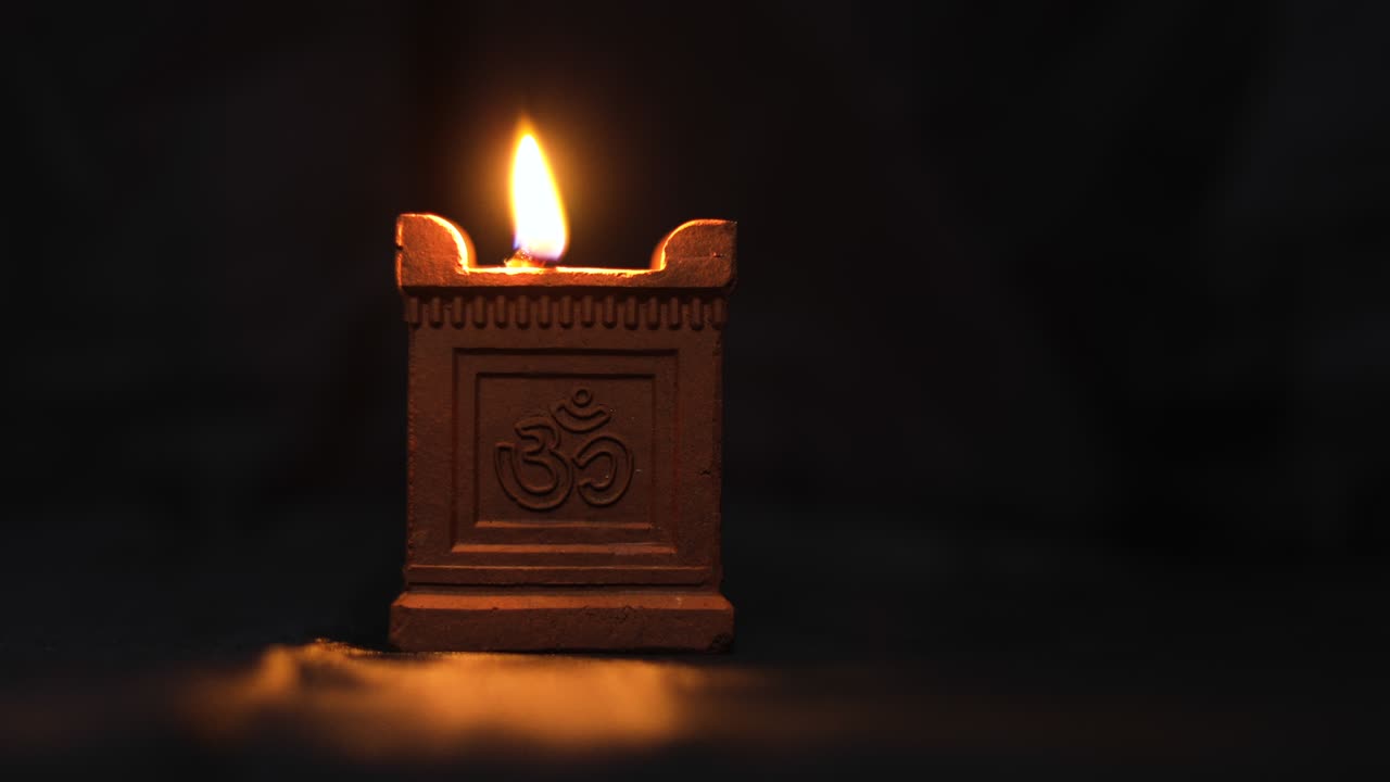 A traditional hand-made oil lamp is lit with the Om symbol used in Deepavali, Maha Shivaratri and many other religious festivals.