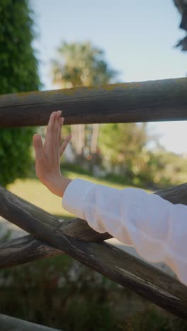 woman's arm and hand gesture near wooden fence