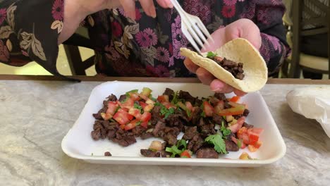 anciana poniendo salsa picante en un taco de carne