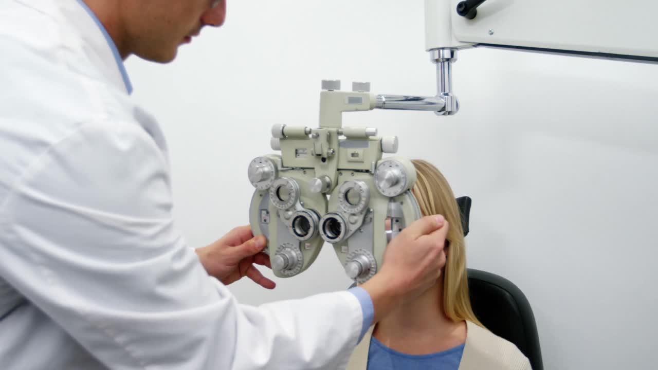 optometrista sonriente examinando a una paciente femenina en el phoropter
