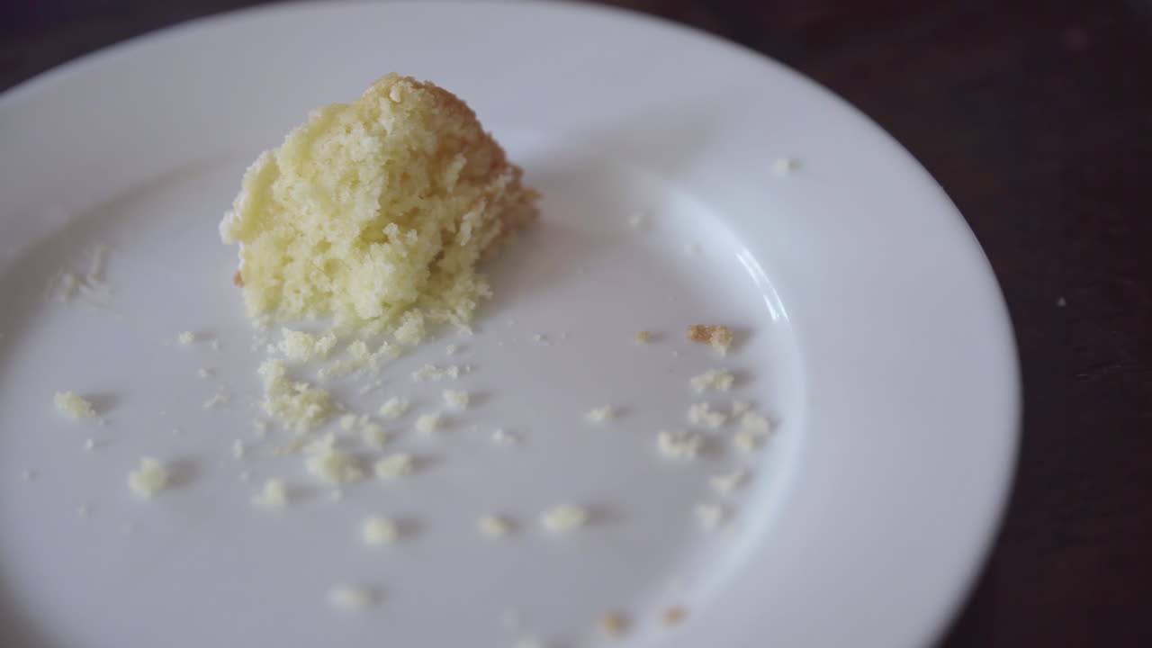 A fork picking up a piece of cake and lifting it out of frame as camera dollies left to right