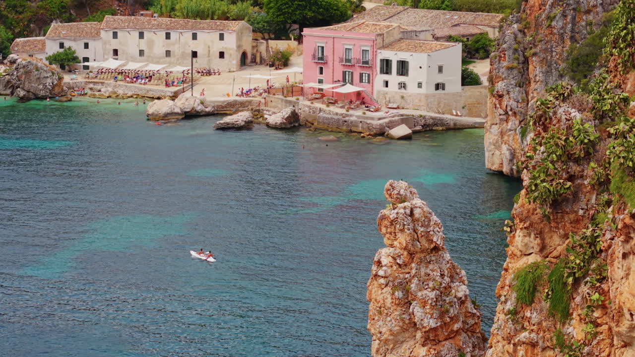 Kayaking in the coastline of Scopello, Sicily. Aerial tilt up