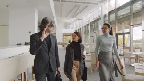 confident businesswoman in casualwear talking two colleagues while they walking