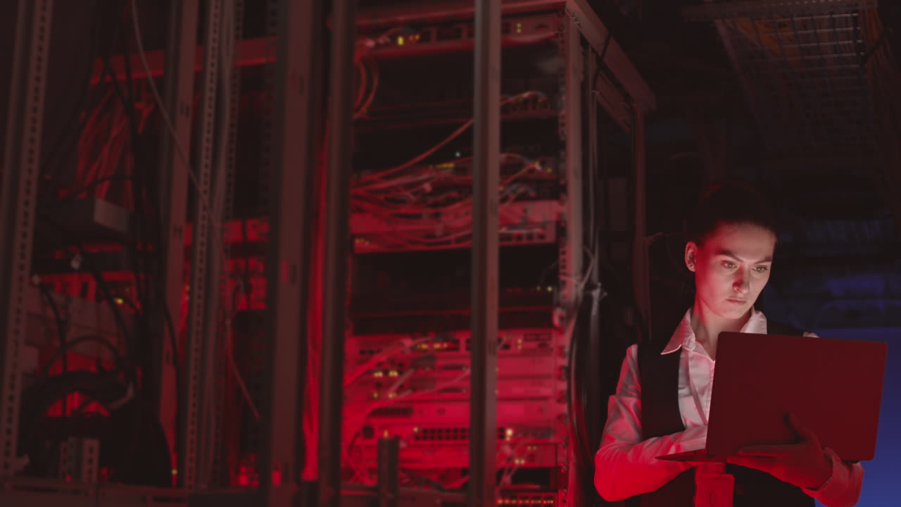mujer trabajando en una computadora portátil en una sala de servidores