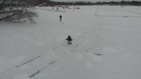 Boy-pulled-by-a-truck-on-a-snow-path