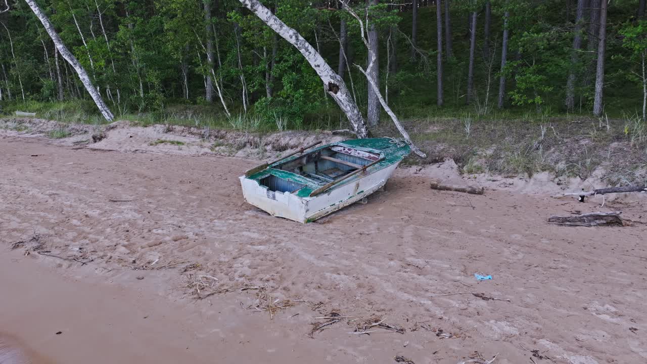 Cinematic shot reveals abandoned boat resting on Baltic shore under sunset sky