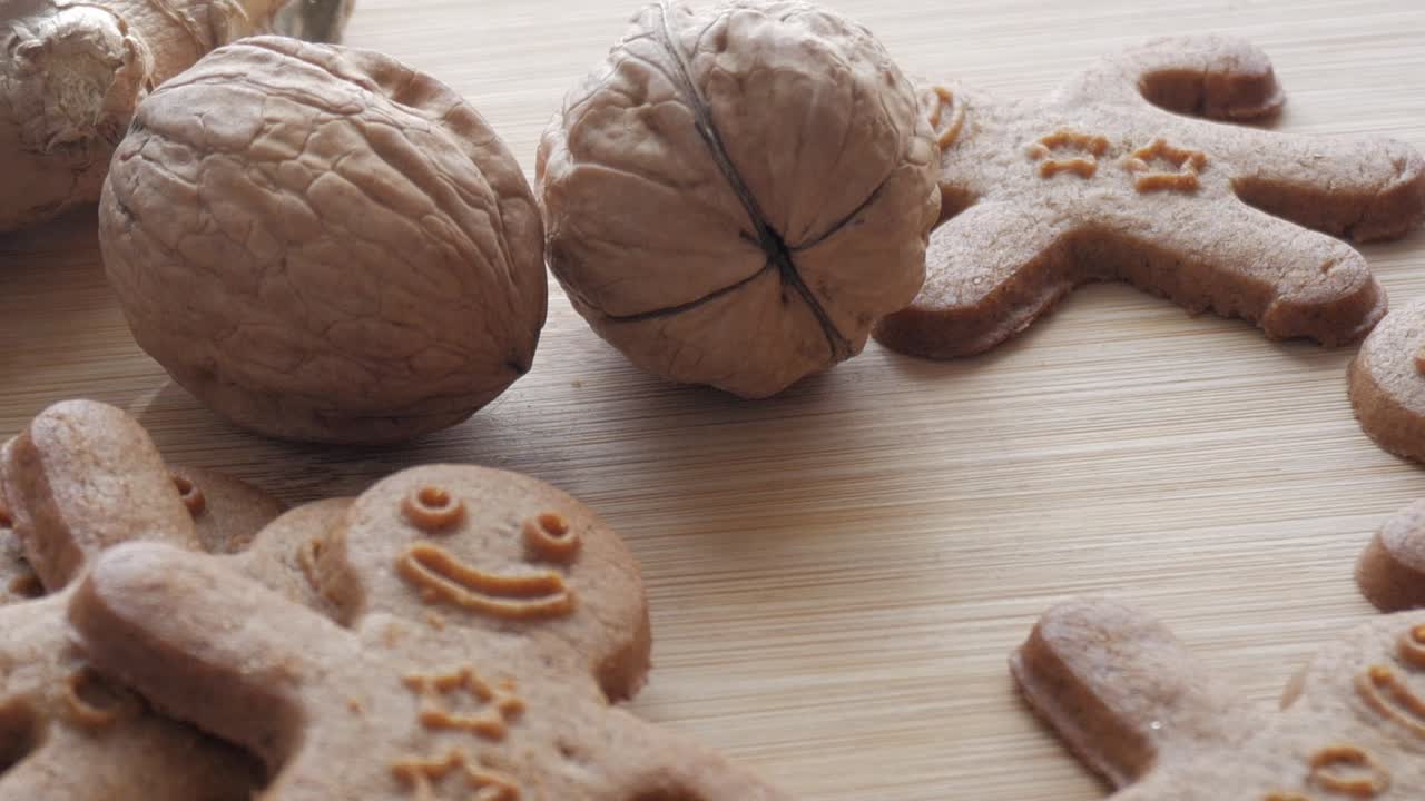 Panning view of gingerbread men cookies on a table with walnuts. Close-up