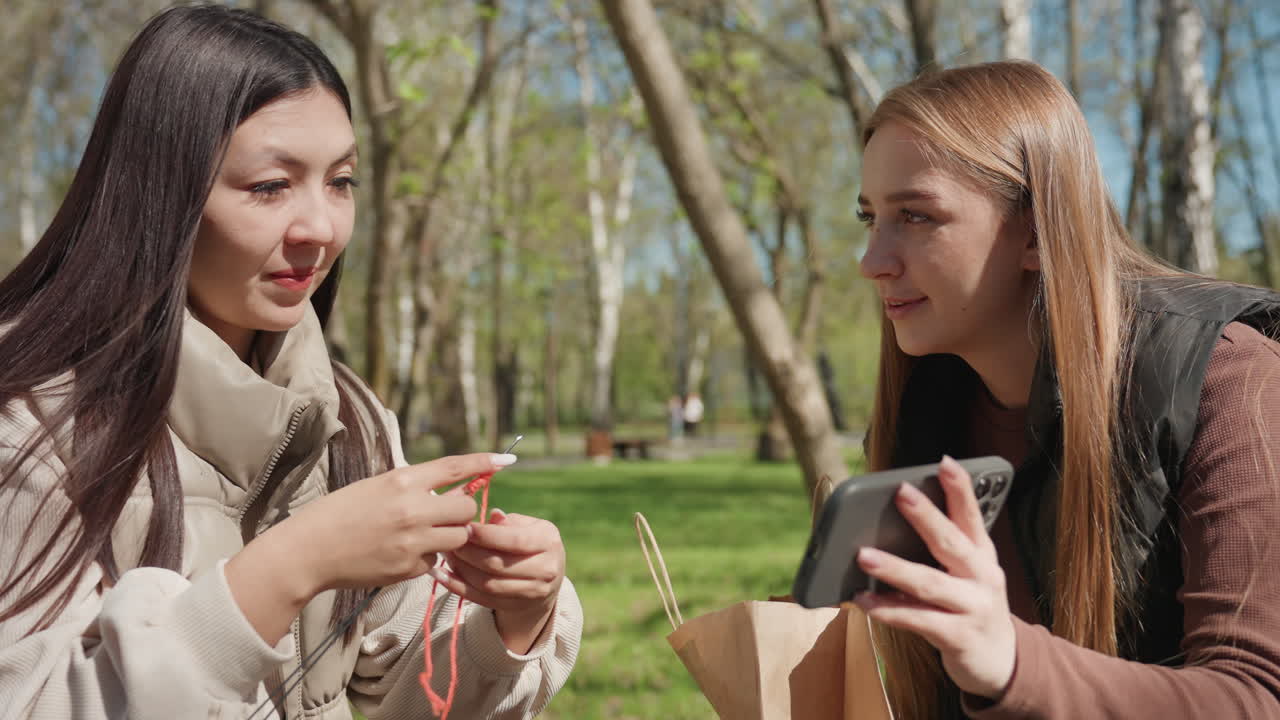 intercambio de pulseras hechas a mano al aire libre, momento de alegría entre amigas con joyas artesanales a la luz del sol, dos amigas compartiendo un gesto cálido con pulseras personalizadas en un parque primaveral